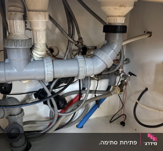 צנרת מתחת לכיור עם חיבורים וצינורות שונים